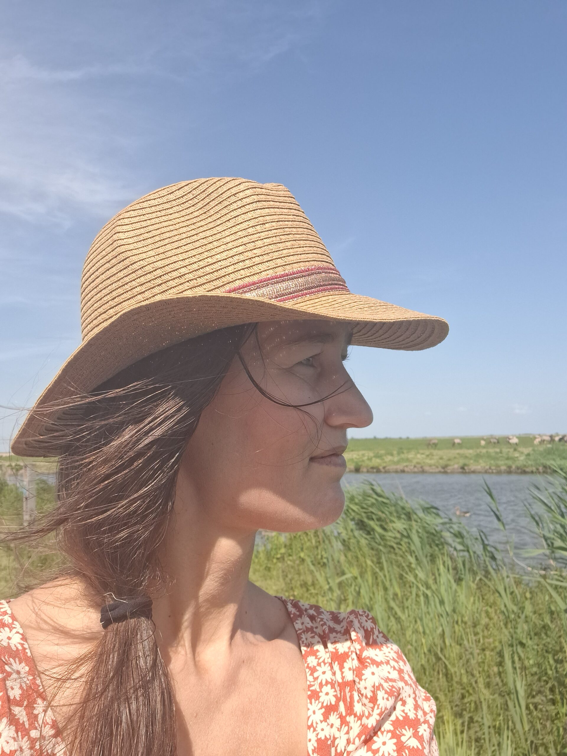 Vrouw met hoed - Lenny van made with YADE - in de natuur. Uitzicht op groen en water.
